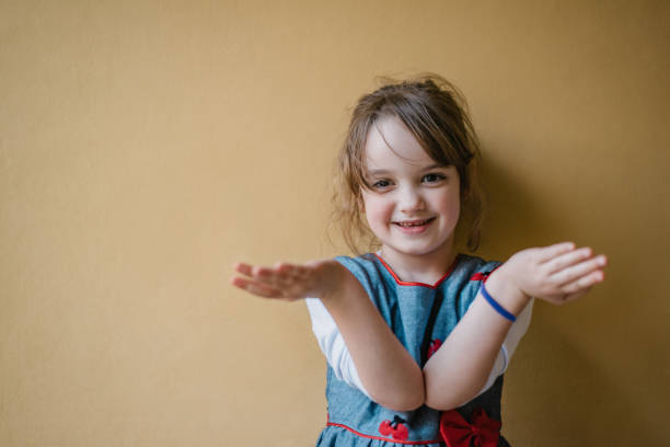 Young blond Caucasian girl showing hello gesture in the window, outdoor closeup monochrome portrait
