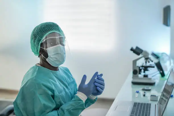 African male doctor working with laptop and protective face mask for coronavirus outbreak - Medical worker