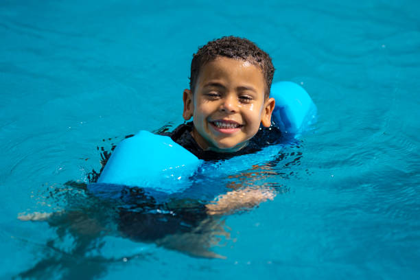 Boy swimming in the pool wearing float Child playing inside the pool wearing buoy looking at the camera swimming protection stock pictures, royalty-free photos & images