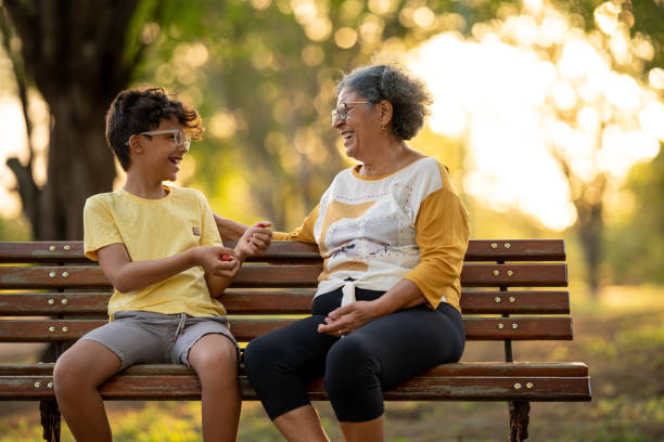 Grandmother and grandson sitting on the bench in the square Grandmother and grandson are sitting in the park talking and smiling young grandparents stock pictures, royalty-free photos & images