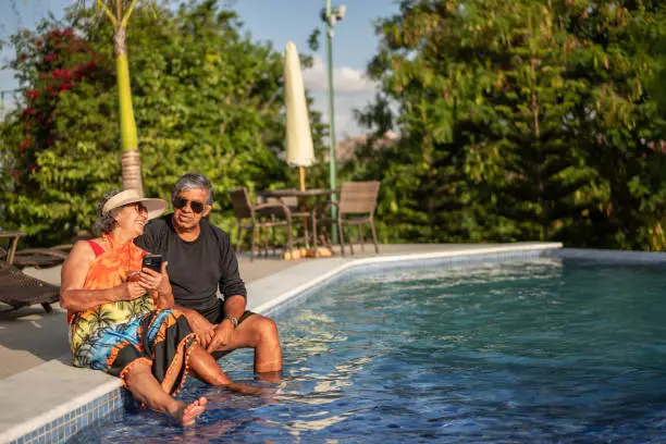 Elderly couple by the pool using smartphone