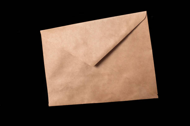 istock Closed brown paper envelope isolated on black background 1311298353