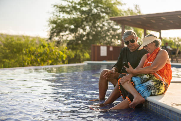 Elderly couple sitting by the pool using smart phone