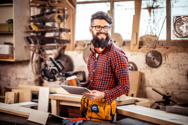 istock Young man at carpentry cutting wood and using digital tablet. 1311298543