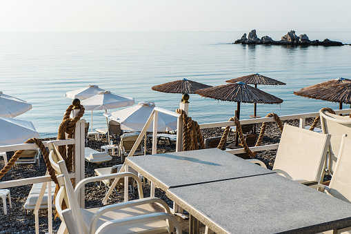 Charaki, Greece - August 31, 2018: Empty restaurant tables by the sea in the early morning