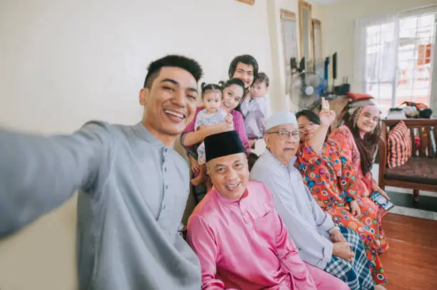 Malaysian malay family taking selfie photo looking at camera waving at home celebrating hari raya