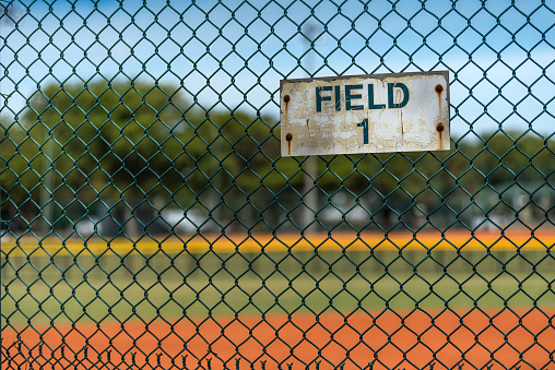 Little league baseball fence with a rusty and weathered field identifier sign.