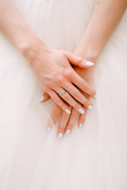 изящные руки невесты, сложенные на пушистой юбке свадебного платья, крупным планом - garment fragility women skirt стоковые фото и изображения