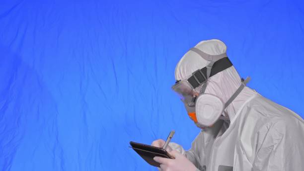 istock Scientist virologist in respirator makes write in an tablet computer with stylus. Man wearing protective medical mask. Chroma key blue. 1311303783