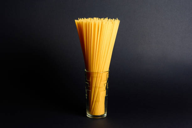 Spaghetti in a glass on a black background, Italian cuisine and cooking.