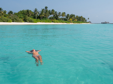 She enjoys the tropical lagoon in the Maldives, arms outstretched