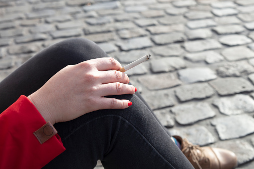 Detail of woman holding a cigarette.