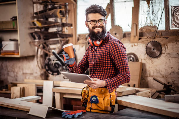 istock Young man at carpentry cutting wood and using digital tablet. 1311309081