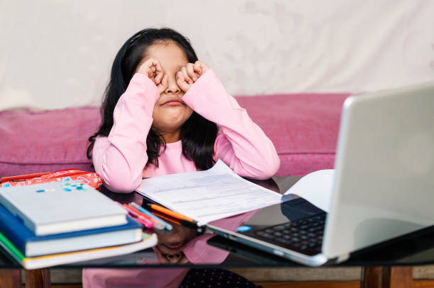 istock A baby girl rubbing her eyes while Online Classes on Laptop 1311310516
