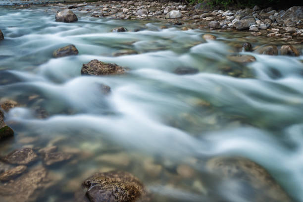 tranquil scene at riverside with blurred motion water - switzerland cold green rock imagens e fotografias de stock