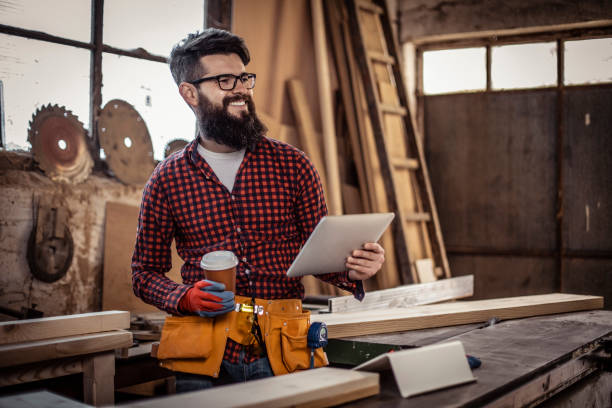 istock Young man at carpentry cutting wood and using digital tablet. 1311312122
