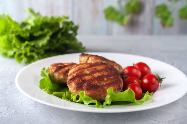 istock Fried cutlet with salad and tomatoes in a white plate on a gray background 1311313831