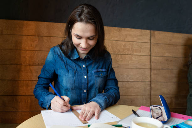 istock a cheerful girl draws a emotions schedule with a blue felt-tip pen using a wooden ruler, in front there is a book and a white mug with green tea 1311314640