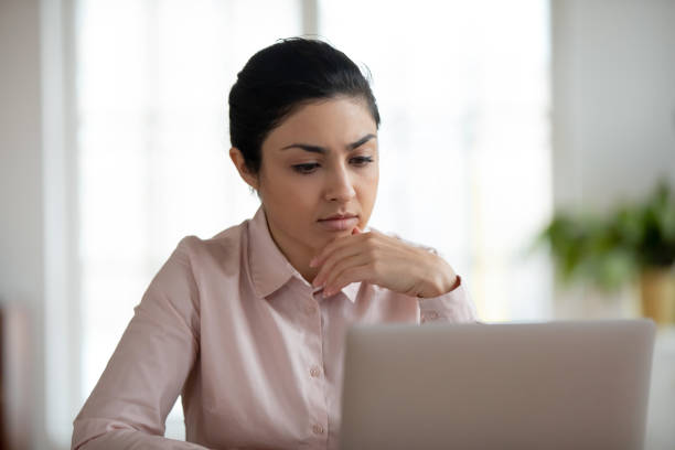 istock Pensive Indian female employee work on laptop thinking 1311315490