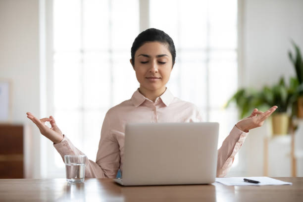 istock Calm Indian woman distracted from computer work meditating 1311315584