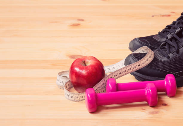 istock Dumbbells, measuring tape, apple and sneakers. Selective focus. 1311316243