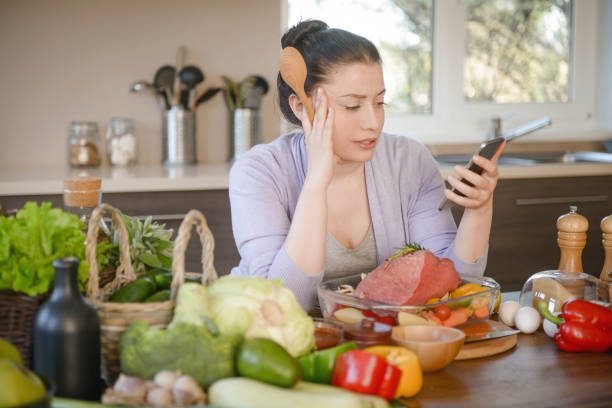 istock woman cooking in the kitchen ( beef and smart phone) 1311316834