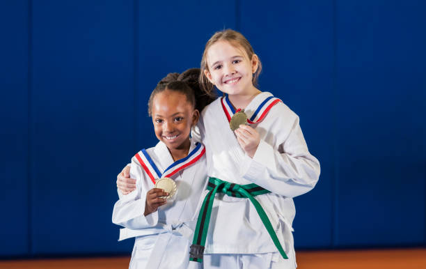 le ragazze vincono la competizione taekwondo - two girls only cheerful front view horizontal foto e immagini stock