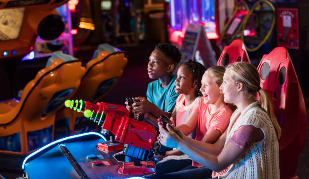 quatro crianças jogando jogo de fliperama de diversão - amusement arcade - fotografias e filmes do acervo