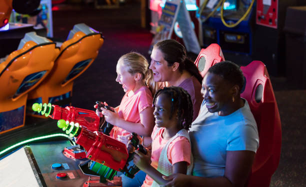 istock Two mothers, daughters playing amusement arcade game 1311317319