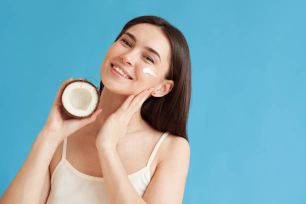 istock Lovely woman with coconut applying moisturizing cream on her face 1311318544
