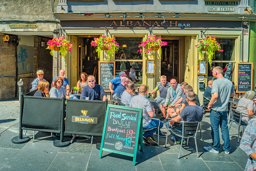 People enjoy restaurant-bar patio on the Royal Mile in Old Town Edinburgh Scotland on a sunny day.