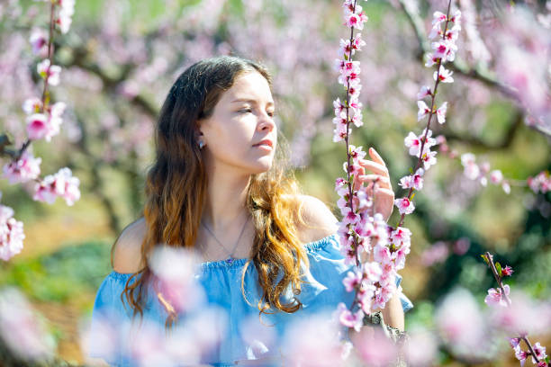 istock Young smiling lady posing in park with blooming trees 1311321224