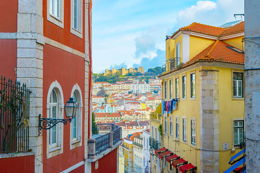 Street and skyline of Lisbon Old Town with Lisbon Castle on a top of a hill. Portugal