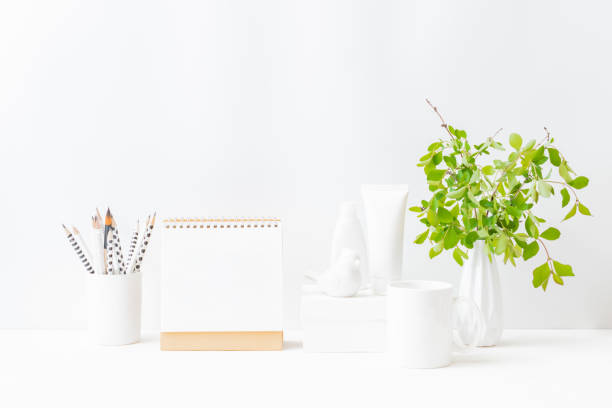 istock Home interior with decor elements. Mockup white desk calendar and branches with green leaves in a vase on a light background 1311322781
