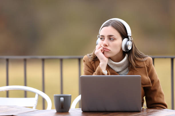 mulher entediada com fones de ouvido e laptop em uma cafeteria - cafe laptop espresso business - fotografias e filmes do acervo