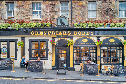 People sit on the patio of the historic Greyfriars Bobby pub in Old Town Edinburgh, Scotland on a cloudy day.