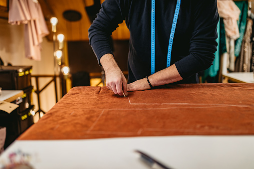 Young fashion designer working in atelier with sewing pattern.