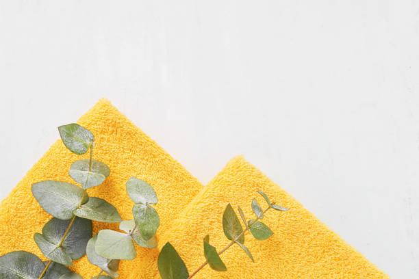 istock Folded yellow towels and green eucalyptus branches on a white background. SPA concept 1311326392