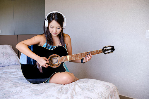 Woman enjoying a relaxing moment with her guitar with musical accompaniment.