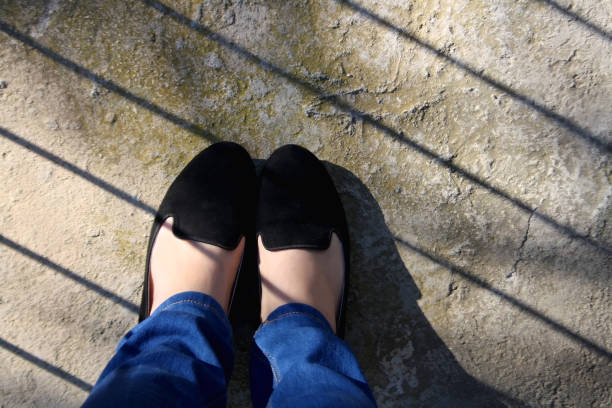 Unrecognizable person wearing jeans and black loafers. Top view.