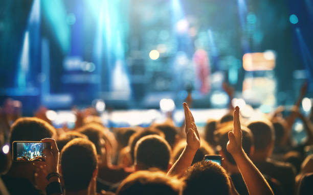 Large group of people at a concert party. Rear view of large group of people enjoying a concert performance. There are many hands applauding and taping the show. entertainment club photos stock pictures, royalty-free photos & images