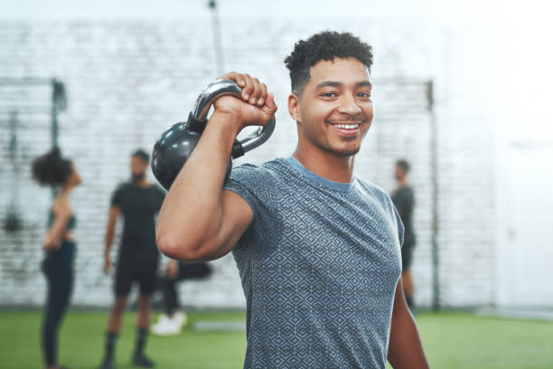 I am getting better day by day Portrait of a young man exercising with a kettlebell in a gym health club stock pictures, royalty-free photos & images