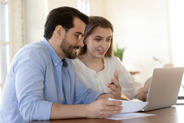 istock Smiling colleagues cooperate on laptop in office 1311330645