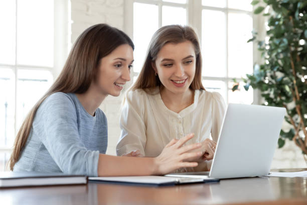 istock Smiling female colleagues work on laptop in office together 1311330647