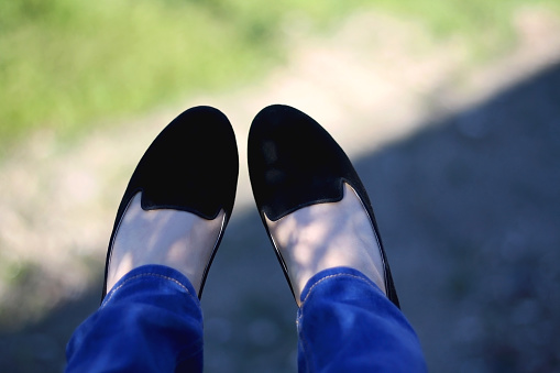 Unrecognizable person wearing jeans and loafers outdoor. Selective focus.