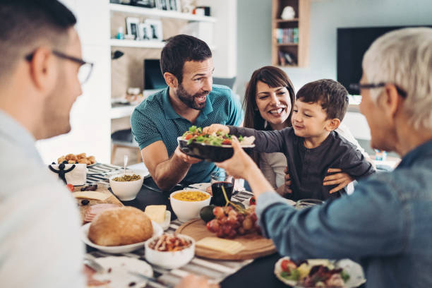 istock Little boy taking salad with his hands during an extended family dinner 1311332587