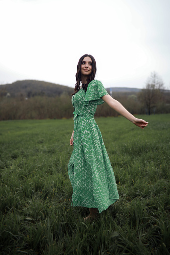 Woman in Green Dress Walks Happily On The Grass