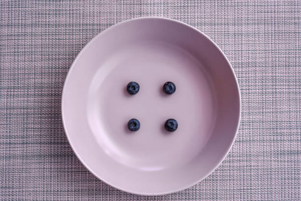 istock Four blueberries on a pink plate - button style photo 1311334834