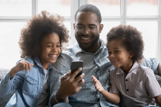 istock Happy millennial black dad and two cute kids using cell 1311335756