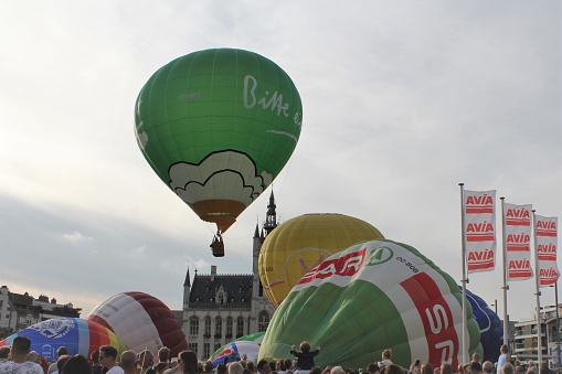 Sint-Niklaas, Belgium - sep 3, 2017: a green hot air balloon is flying up in the air from the market square in sint-niklaas during the annual peace festivities